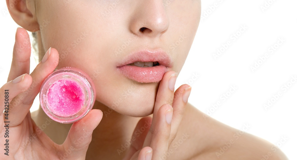 Beautiful young woman with clean perfect skin uses lips sugar scrub. Isolated on white. Spa, skincare and wellness. Close up - obrazy, fototapety, plakaty 
