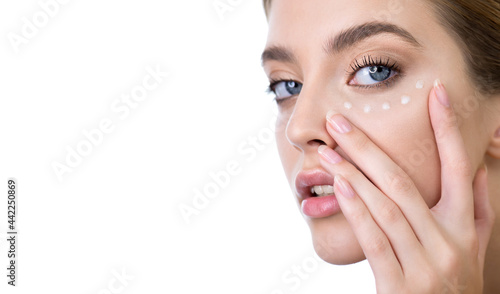 Young woman applying eye cream on her face. Beauty model with perfect fresh skin and long eyelashes cares about her skin, isolated on white. Spa and Wellness, Skin Care Concept