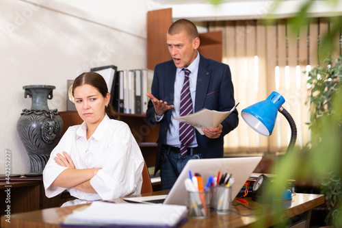 Dissatisfied manager scolding frustrated female assistant in office