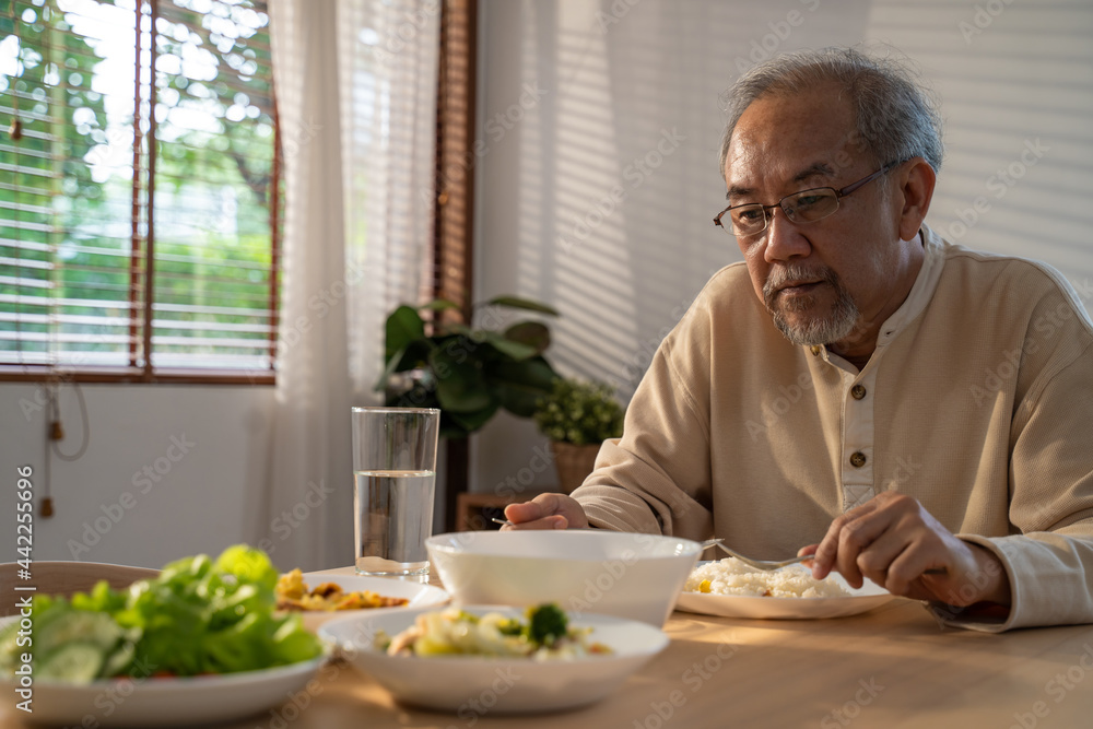 Unhappy Asian Senior older man sit alone, eat foods on table in house. Unhappy Asian Senior older man sit alone, eat foods on table in house.