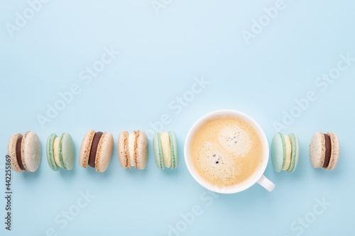 Creative flat lay. Cup of coffee, various macarons on blue background. Copy space for your text