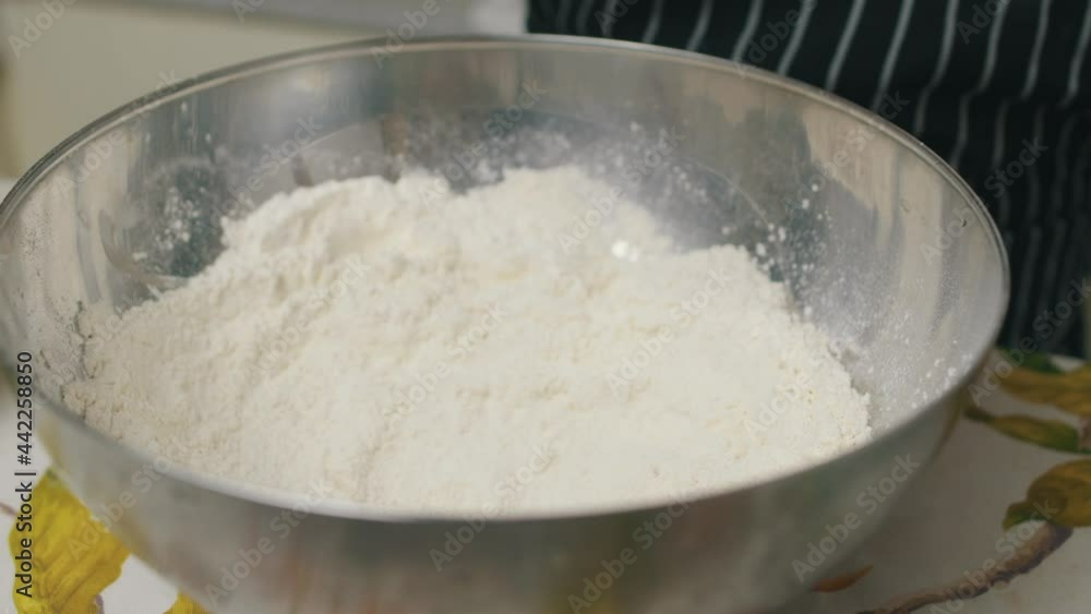 Chef moves chicken meat from sauce bowl into bowl with flour. Chef moves chicken meat from sauce bowl into bowl with flour.