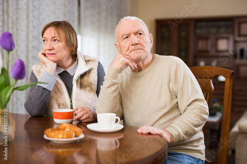 Upset elderly man sitting separately having problems in relationship with spouse..
