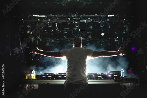 DJ with arms outstretched in foggy nightclub