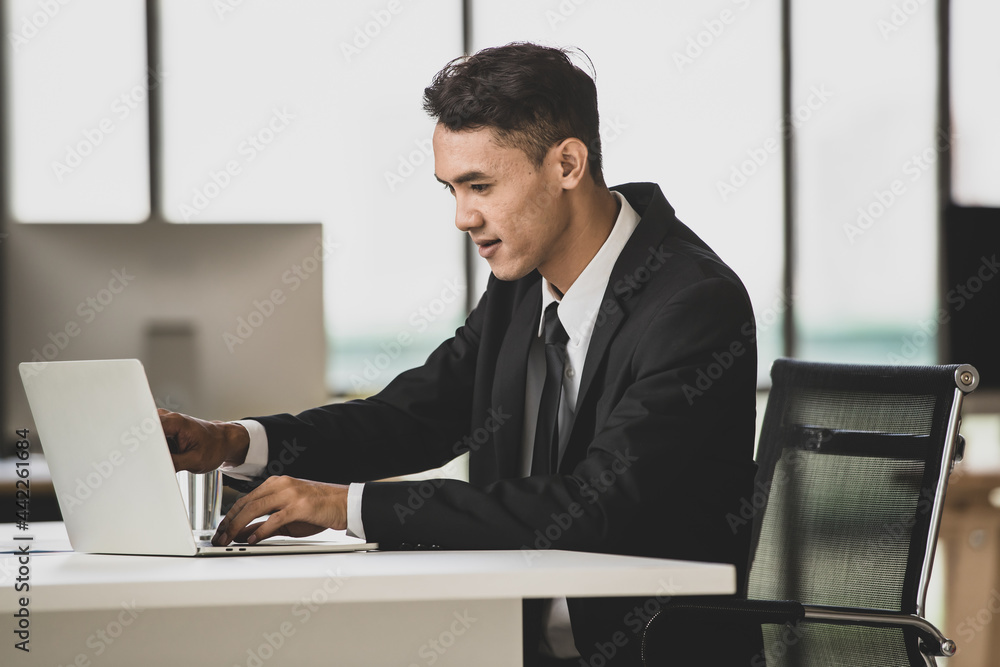 Cheerful businessman typing on laptop in office Cheerful businessman typing on laptop in office