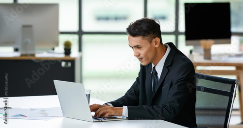Cheerful businessman typing on laptop in office
