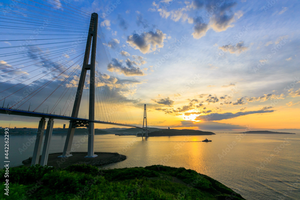 Russian bridge across the Eastern Bosphorus Strait in Vladivostok. Colorful sunrise on the background of the roadway of the Russian bridge.