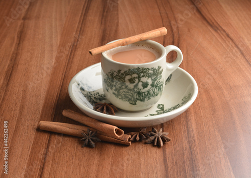 hot masala chai milk tea in traditional ceramic cup with cinnamon and star anise on wood table hot healthy asian beverage menu 