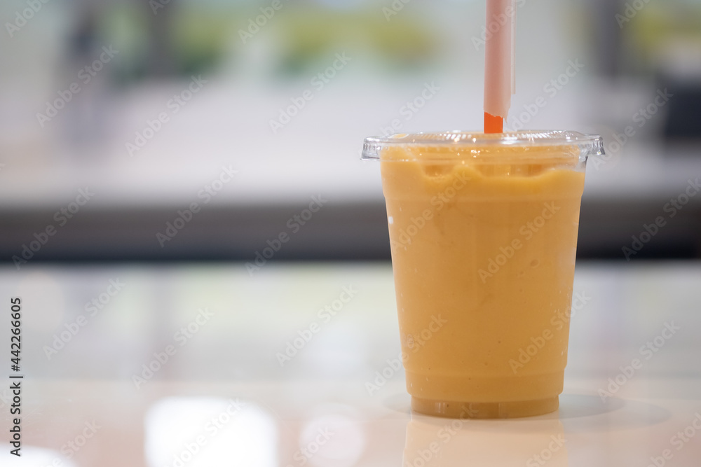 Orange, banana and mango smoothie in a plastic glass Orange, banana and mango smoothie in a plastic glass