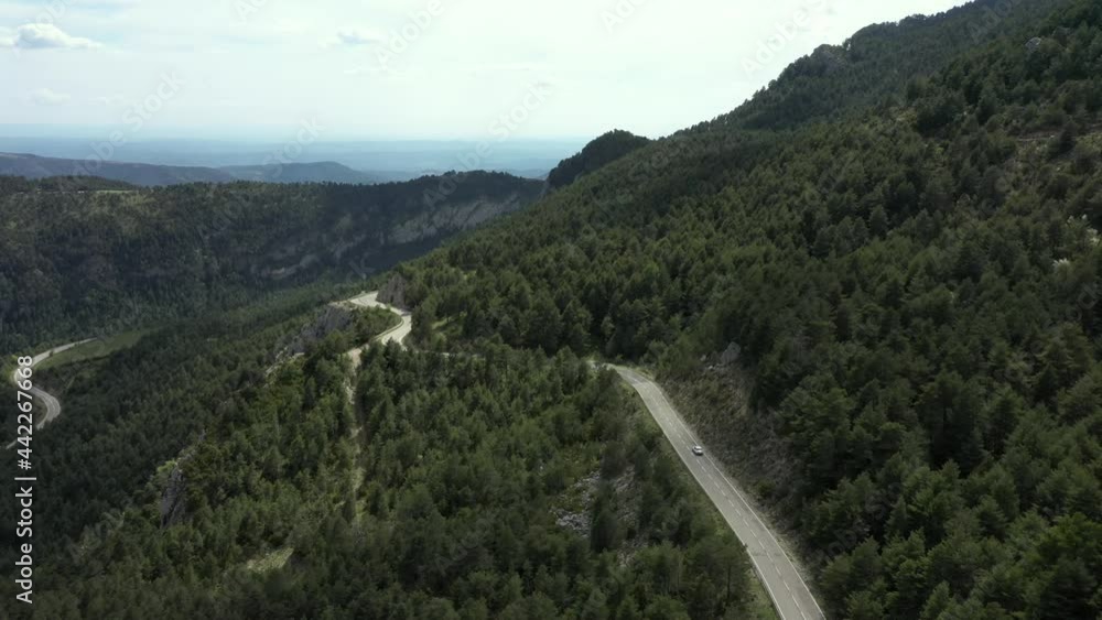 Aerial View Of Fast Moving White Car On The Road Passing The Forrest On Daytime - drone shot Aerial View Of Fast Moving White Car On The Road Passing The Forrest On Daytime - drone shot