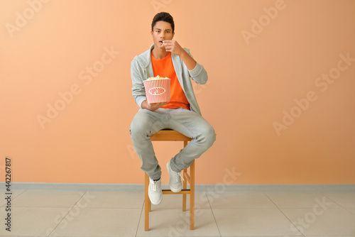 African-American teenager eating popcorn near color wall © Pixel-Shot