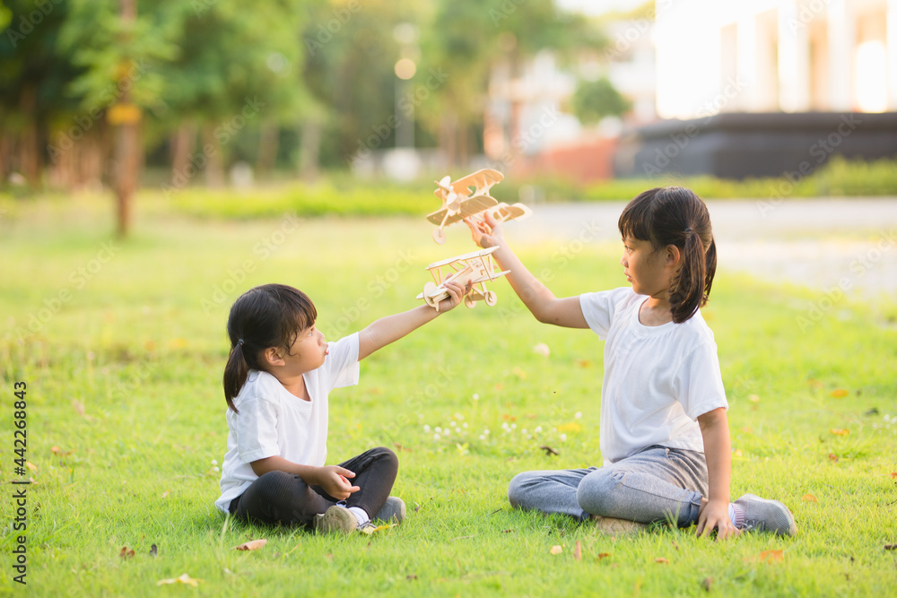 Two little kids playing with cardboard toy airplane in the park at the day time. Concept of happy game. Child having fun outdoors. Two little kids playing with cardboard toy airplane in the park at the day time. Concept of happy game. Child having fun outdoors.
