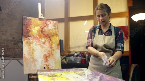 Woman artist is taking off her painting glosves after aristic workshop and leaving. The job is done. photo
