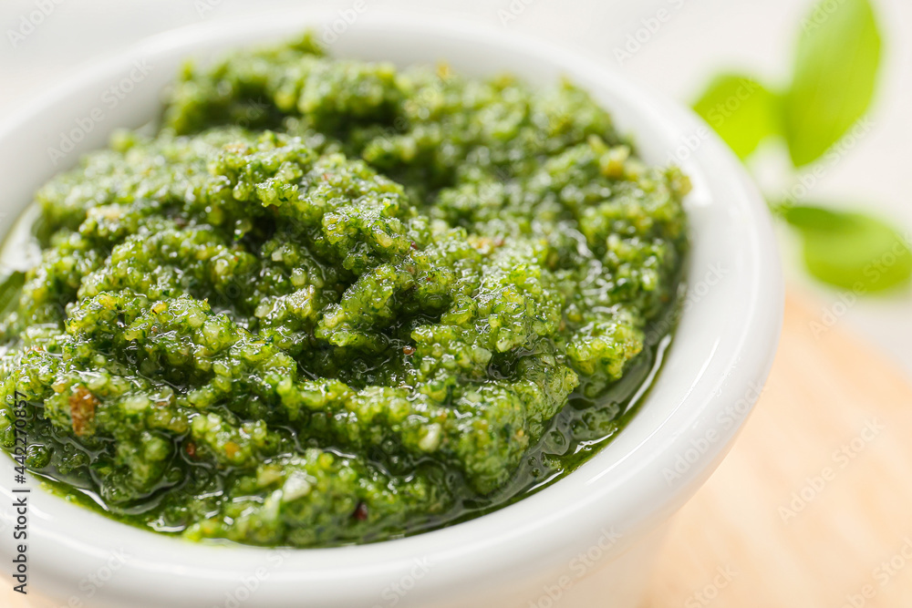 Wooden board with fresh pesto sauce on light table, closeup Wooden board with fresh pesto sauce on light table, closeup