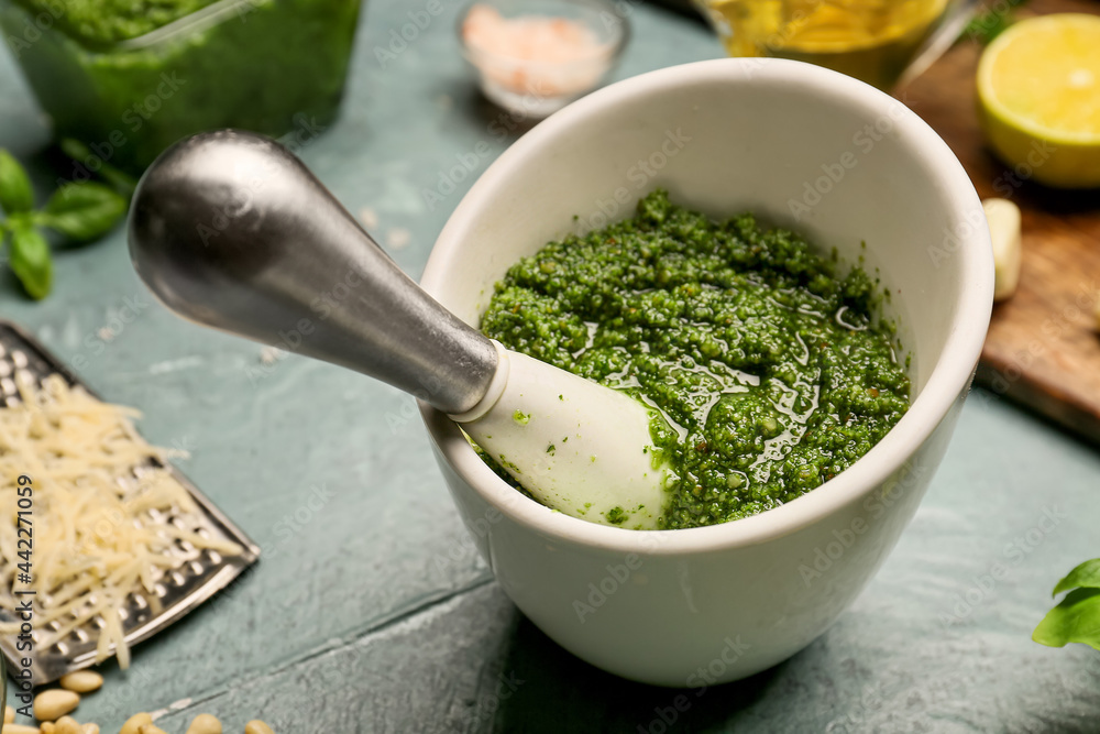 Mortar and pestle with fresh pesto sauce on wooden background