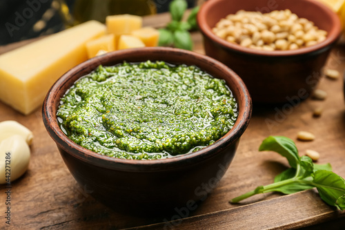 Board with fresh pesto sauce and ingredients on wooden table