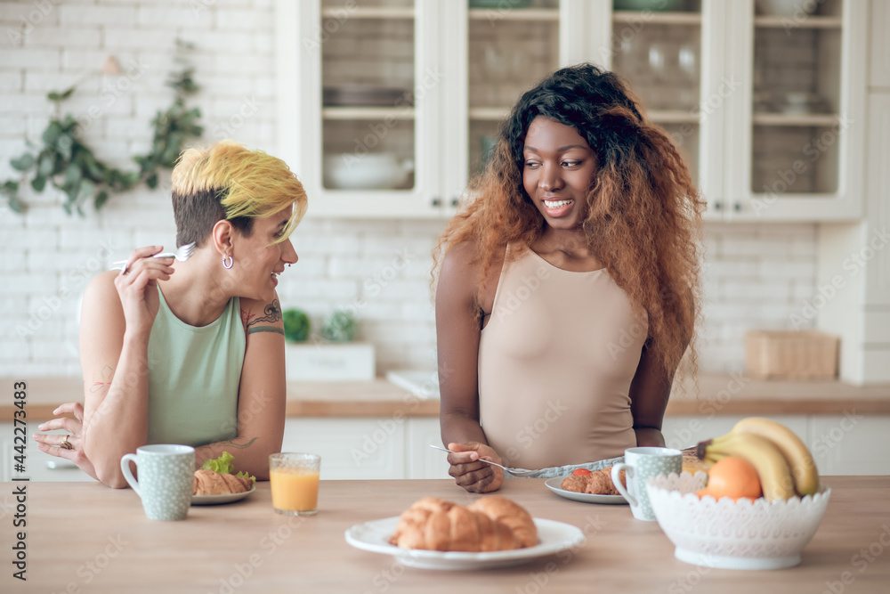 Two girlfriends having breakfast in morning in kitchen Two girlfriends having breakfast in morning in kitchen