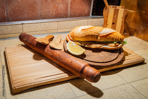 Milanesa argentinian steak sandwich with salad, tomatoes, cheese, egg, lemon, sausages, chips. Truck food. Fast food. Selective focus.