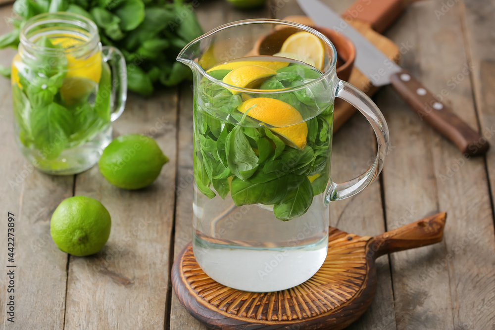Fototapeta premium Jug of lemonade with basil on wooden table