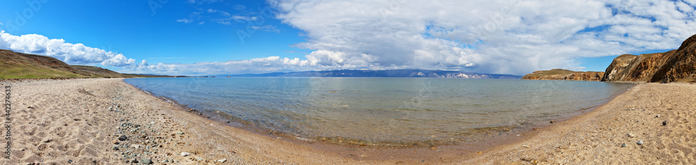 Panoramic view on sandy beach of the shallow bay of Baikal Lake. Olkhon Island and the Small Sea Strait on sunny day. Beautiful summer landscape. Natural background. Travel and vacation concept