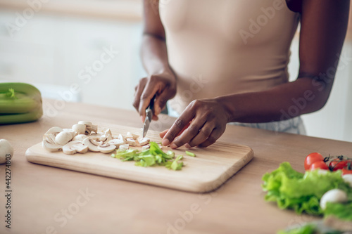 Fototapeta Naklejka Na Ścianę i Meble -  Hands of african american woman chopping vegetables with knife