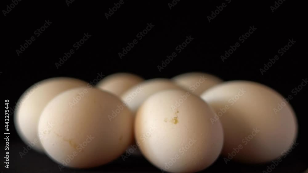 White chicken eggs spinning on a black background close up White chicken eggs spinning on a black background close up