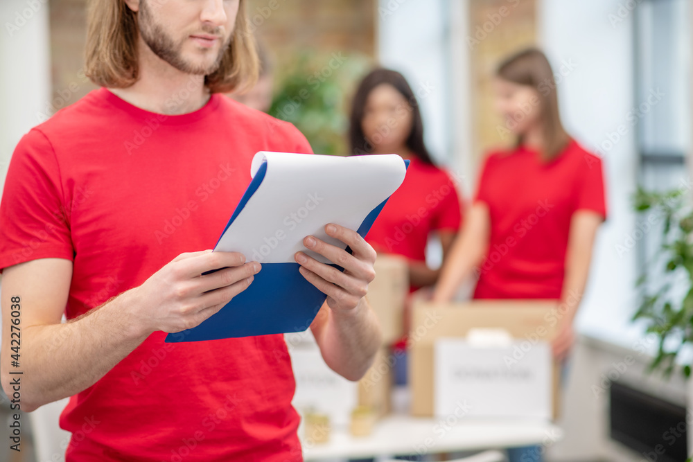 Guy studying document and girls volunteers behind Guy studying document and girls volunteers behind