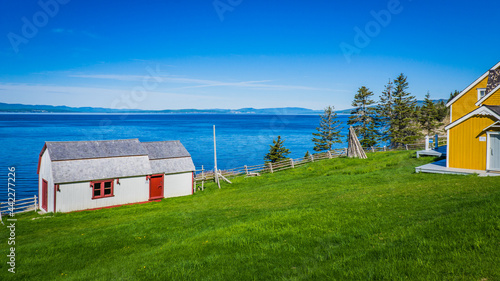 Barn and old house at Grande Grave, in Forillon National Park near Gaspé (Quebec, Canada), with view on the ocean on a sunny summer day photo