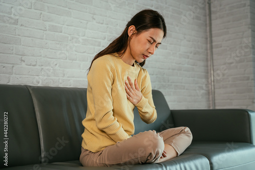 Photography Asian young woman feeling discomfort as suffering from heartburn holding chest w