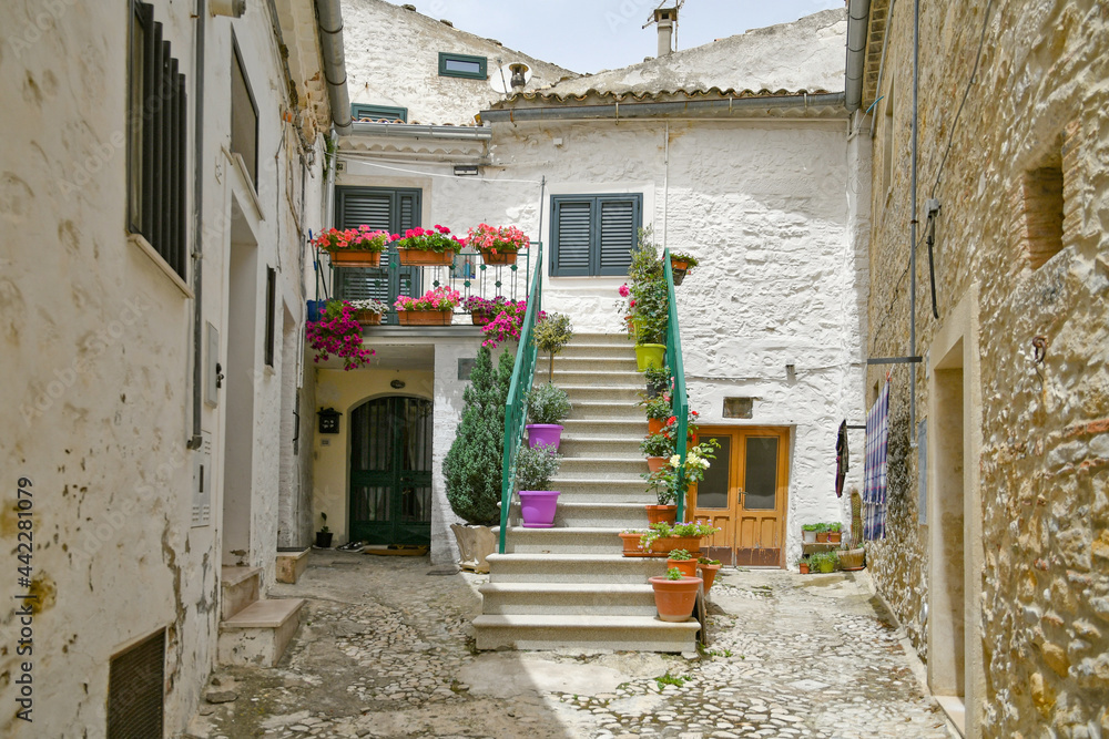 Fototapeta premium Bovino, Italy, 06/23/2021. A narrow street among the old houses of a medieval town with a Mediterranean style in the Puglia region.