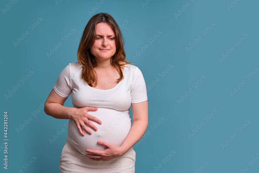 Premature contractions in pregnant woman, studio shot on blue background Premature contractions in pregnant woman, studio shot on blue background