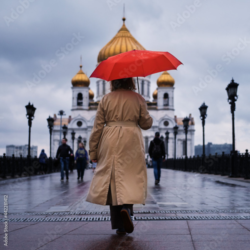 Fotografija An adult woman with a red umbrella goes to the Cathedral of Christ the Savior