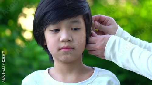Mother Inserting Hearing Aid In The Ear Of Her Son