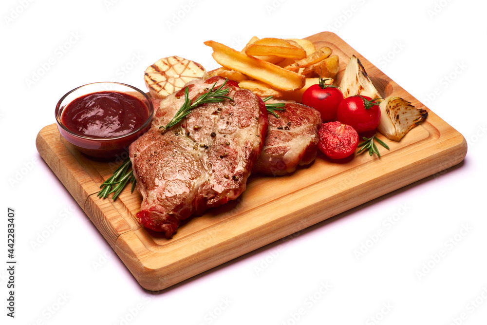 Grilled roated beef steaks, potato and sauce on wooden cutting board