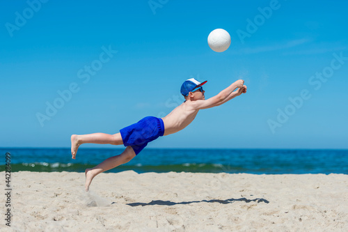 Young boy playing volleyball on beach. Summer sport concept.