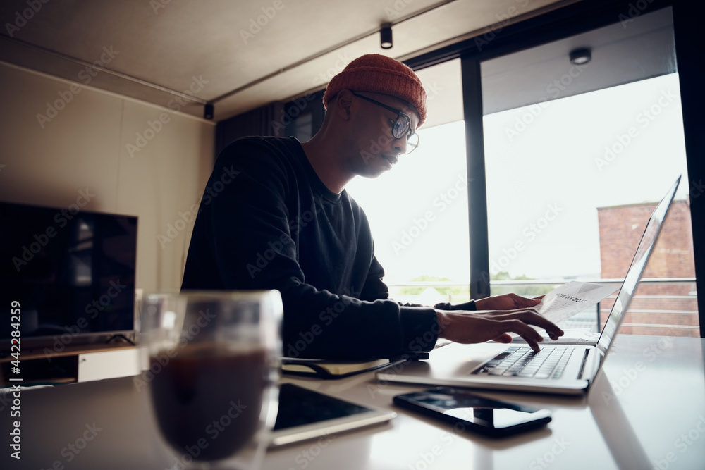 African American male working from home and typing on his laptop. African American male using electronics to work from home. High quality photo