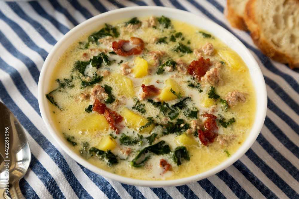 Homemade Zuppa Toscana with Kale and Bread in a white bowl, low angle view. Homemade Zuppa Toscana with Kale and Bread in a white bowl, low angle view.