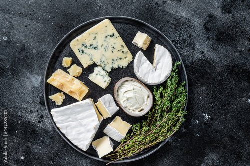 French Cheese plate. Camembert, Brie, Gorgonzola and blue cream cheese. Black background. Top view