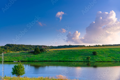 Beautiful summer landscape, beautiful view of the lake, surrounded by meadows and green forest. Blue sky over plain, nature, background