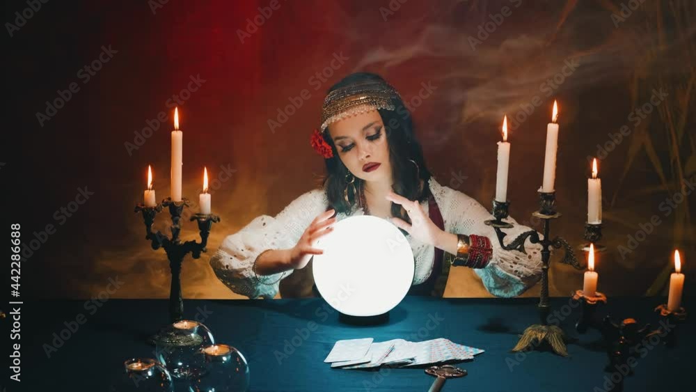 Fantasy witch beautiful gypsy girl, predicts fate, feel energy of crystal ball in dark gothic room. Mystical old art vintage astrology. Fortune teller woman reading future. magic light, tarot cards.