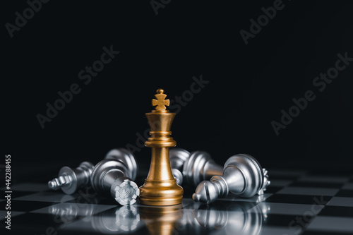 Gold king winner surrounded with silver chess pieces on chess board game competition.concept strategy  leadership and success business.