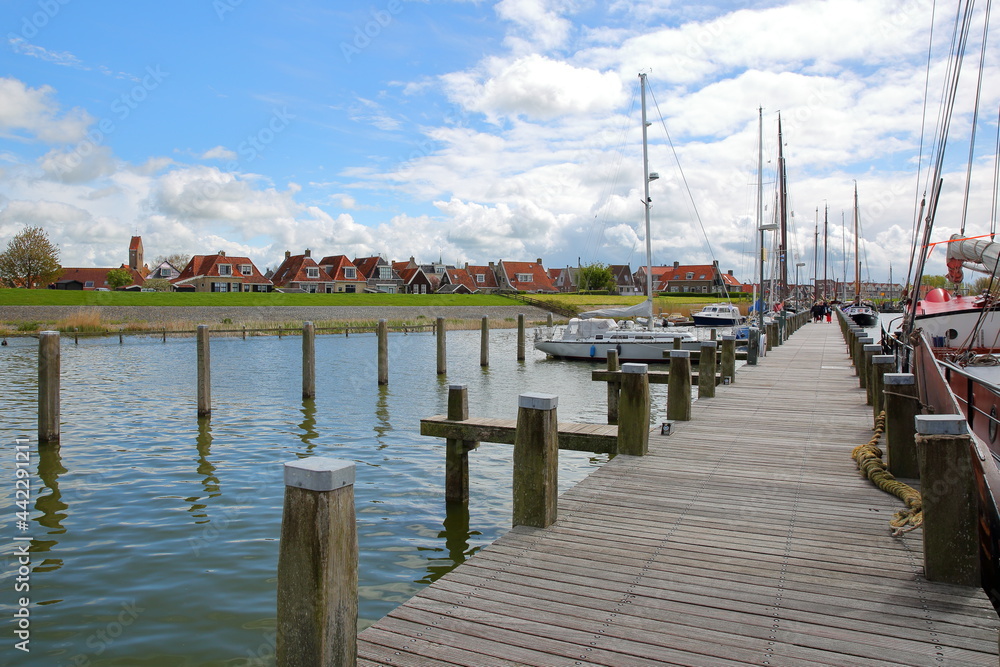 The harbor with sailing boats in Makkum, Friesland, Netherlands, and with traditional houses in the background