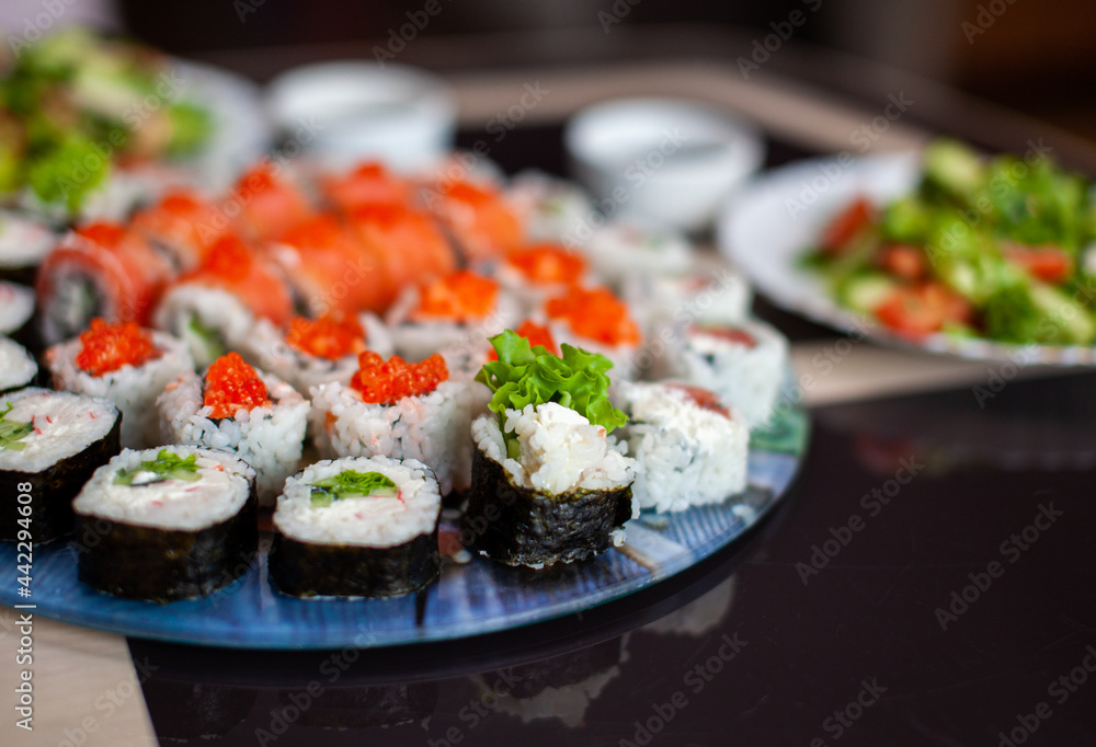 Making sushi and rolls at home. Sushi with seafood, salad and white rice. Food for family and friends. A set of different rolls and sushi on a tray. Making sushi and rolls at home. Sushi with seafood, salad and white rice. Food for family and friends. A set of different rolls and sushi on a tray.