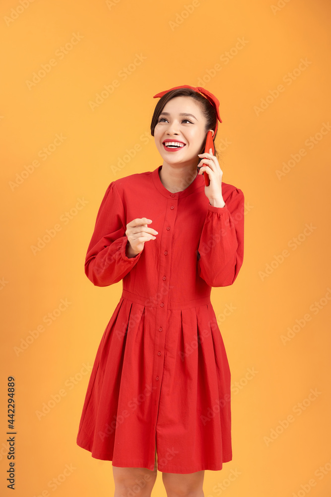 Portrait of a smiling young casual woman talking on mobile phone isolated over yellow background Portrait of a smiling young casual woman talking on mobile phone isolated over yellow background