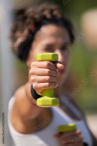 Portrait of athlete strong woman in white dress holding dumbbells