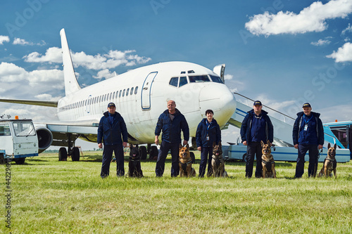 Security officers with dogs standing at airfield