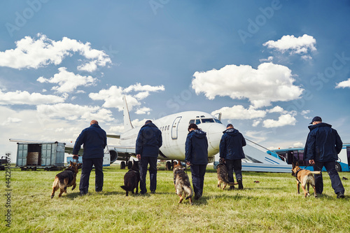 Security officers with detection dogs checking territory of airfield © Svitlana