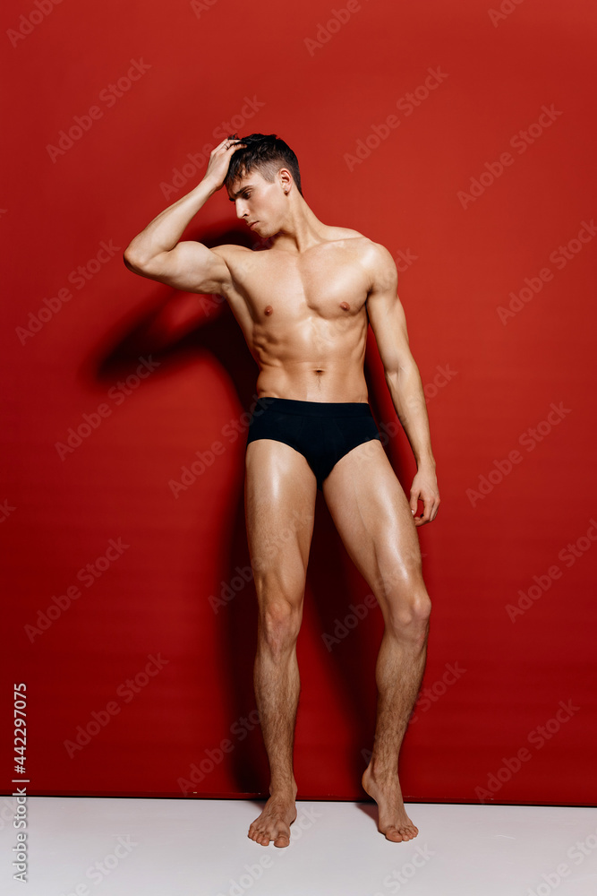 guy with pumped up arm muscles pagebuilder in black panties in full growth on a red background guy with pumped up arm muscles pagebuilder in black panties in full growth on a red background