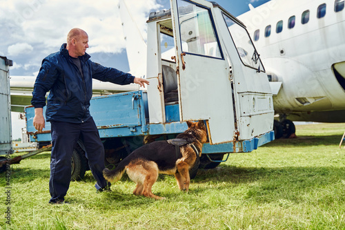Security officer and detection dog checking truck at aerodrome