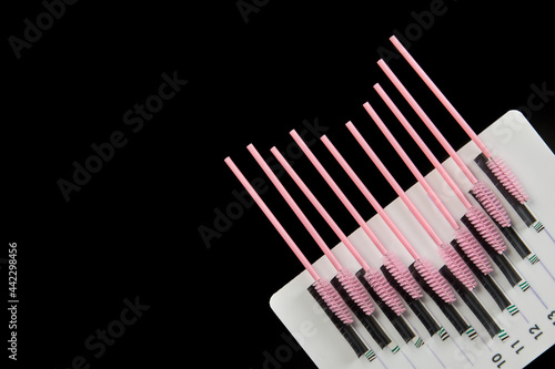 Tablet with false eyelashes and brushes on a black background. Cosmetic accessories for eyelash extensions